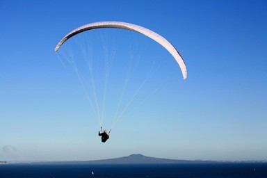 Mark Meredith; Paragliding over Rangitoto; A paraglider at Shakespear Regional Park appears to be gliding over Rangitoto
