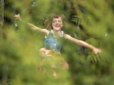  Rather than get up and move to snap my daughter bouncing on a trampoline, I decided to play with the depth of field to resolve the subject and throw the foreground bush out of focus, lending a natural softness to a moment of childish delight