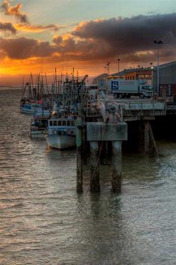 Steve Lawton;Sunset; The sun sets over a fleet of fishing boats moored at the Onehunga Wharf.