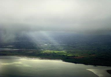 Hannah Andersen; Holes; Sunlight streams through the grey clouds over the Manukau harbour   Taken from plane
