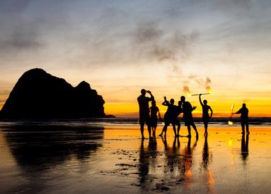 Nazar; Sunset with fire; some people playing with fire at Piha beach.