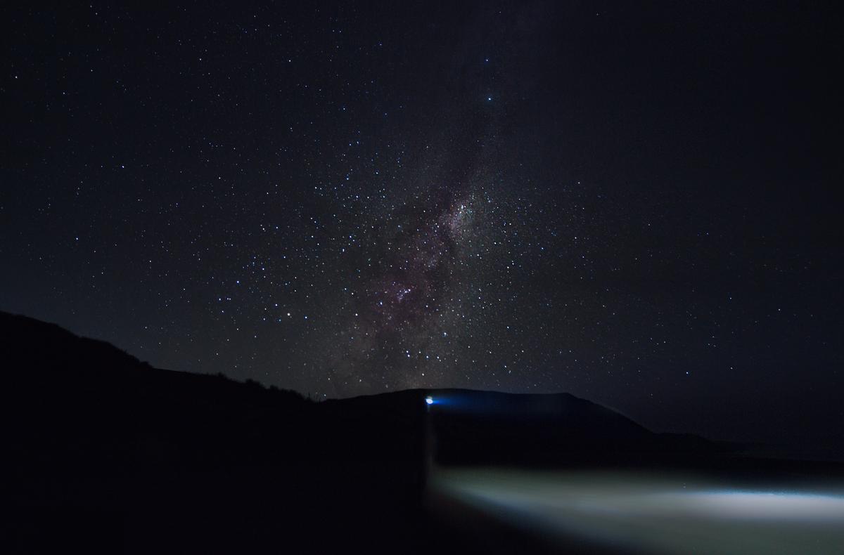 Tre Brett Merlo; “Blind to Nature’s Torch”   “Matapo ki te rama taiao”;I wanted to capture a photograph that portrays a unique perspective of “Xenophobia” or more commonly known as “Fear of the Unknown”. “Blind to Nature’s Torch” captures a beautiful shot of the milky way, with a figure positioned in the foreground, using a head torch to illuminate a narrow area before them. The title “Blind to Nature’s Torch” is influenced by the xenophobia I felt when I captured this photograph, the fear of the dark, the unknown. My first instinct was to wear a head torch so the surrounding area was visible, however the light limited my perspective of the stars (nature’s torch) above. It wasn't until I turned the head torch off that I awoke to the beauty of the night sky as it illuminated the surrounding environment. This experience of being awoken to the beauty in the unknown, has become a common occurrence in photography for me. Photography has not only allowed me to tame fears, but has opened my e