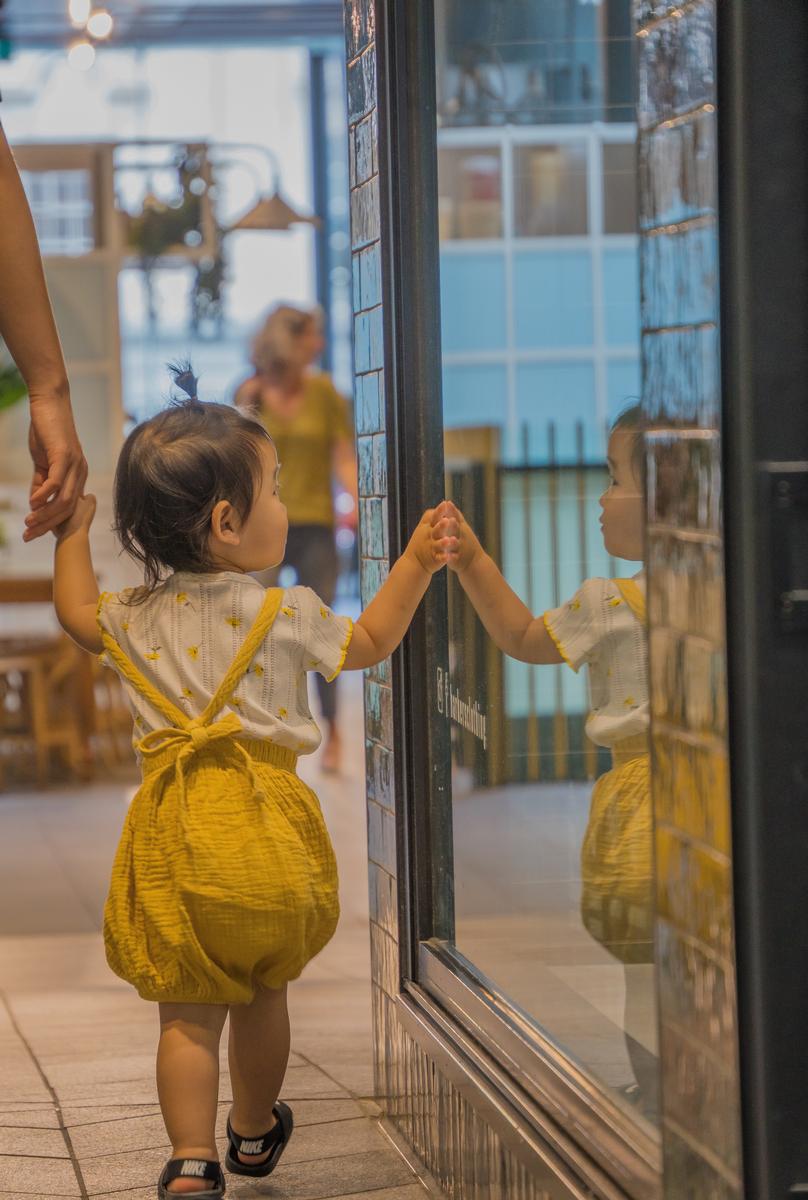 LEYAO LIU;Curious Child;A four year old girl holding her mother’s hand and touching a shop window’s glass. She looks at the display with wonder and curiosity. This photo captures the essence of childhood: exploring the world and learning new things.