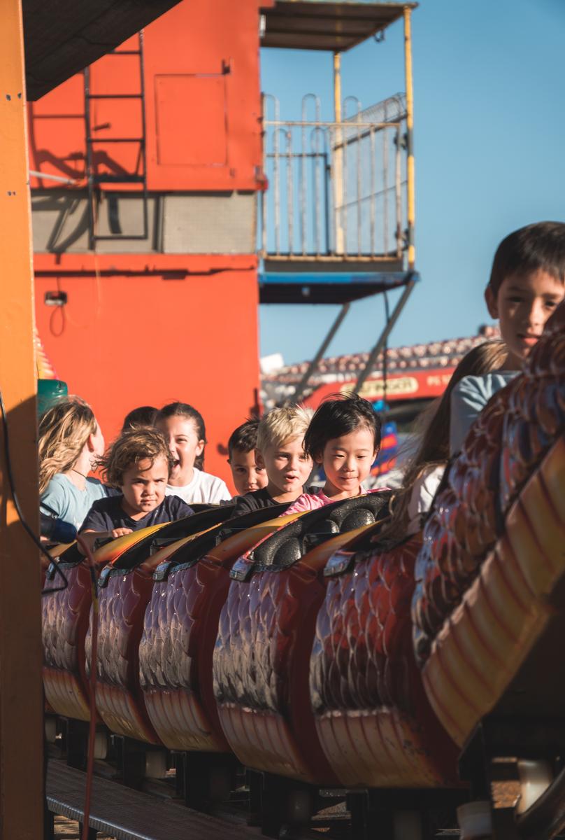 LEYAO LIU;Kids Just Wanna Have Fun;A charming photo of a bunch of kids on a small scream machine at the Hamilton hot balloon event. The photo shows their different reactions to the ride, from happy to calm to serious to screaming, as they have fun in their own ways.