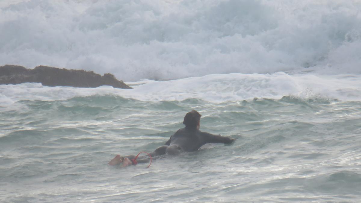 Indi Nicholas;Silent strength ;A lone surfer lies on their board, facing the powerful waves ahead. This image captures a quiet moment of courage and determination. Despite the crashing surf and looming rocks, the surfer remains calm, ready to move forward. It reflects strength, resilience, and the human ability to face challenges with patience, even when the path ahead feels uncertain.