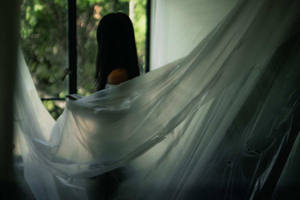 Lucas Lin;Coverage;22/03/25. Shrouded in soft light and sheer fabric, a soft figure stands poised between shadow and serenity