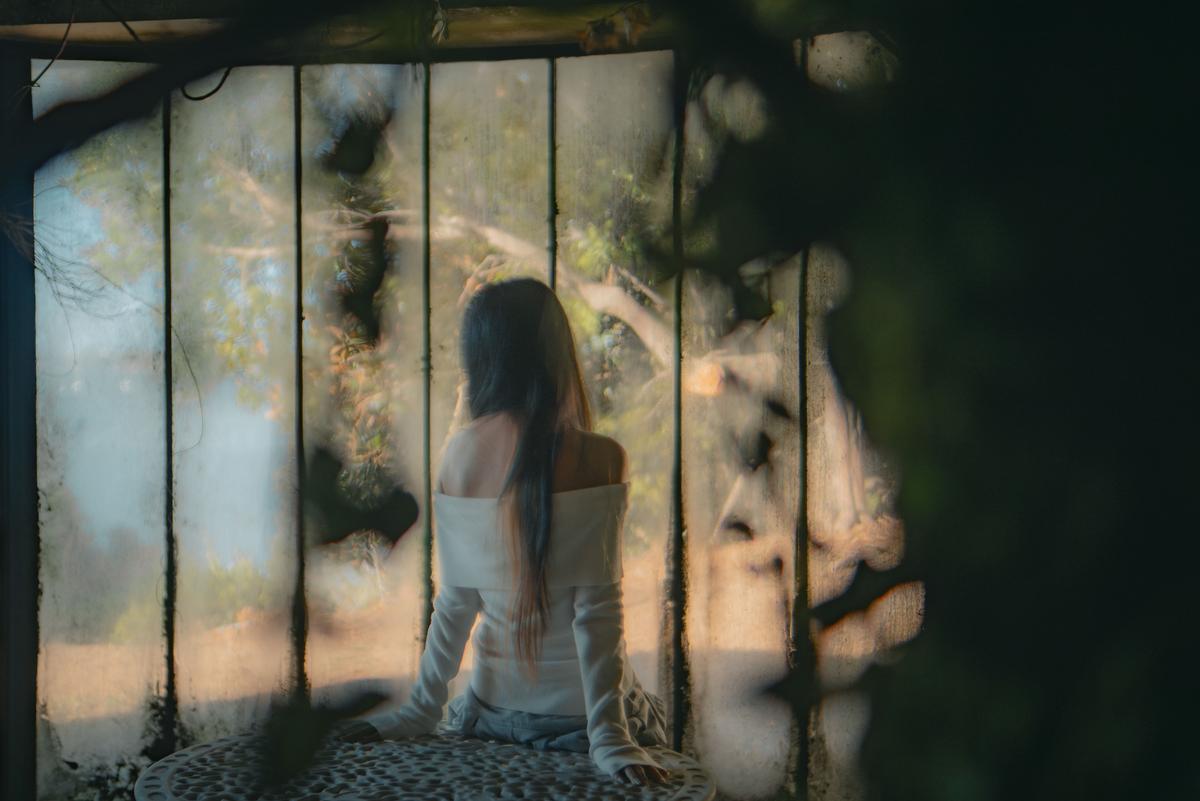 Lucas Lin;Green seat;22/03/25.  Bathed in soft light, a quiet figure gazes through dusty glass, blurring the boundary between reflection and reality.