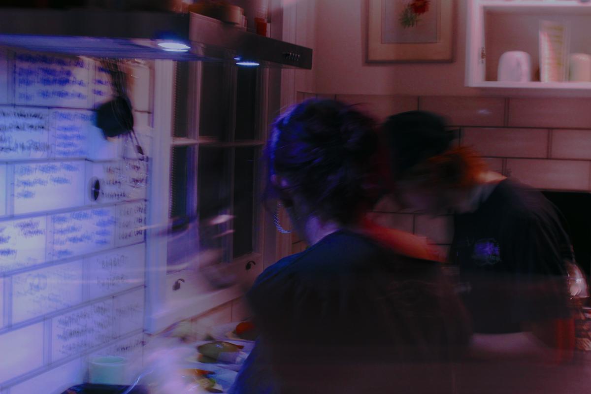 Uriel de Proença Ruiz;Soft Chaos;Captured in the kitchen frenzy during a night of celebration, this photo holds the warmth of a chosen family. A blur of movement, laughter, and unspoken rhythm, all combined to create a glimpse into queer collectivity while celebrating with a special menu.