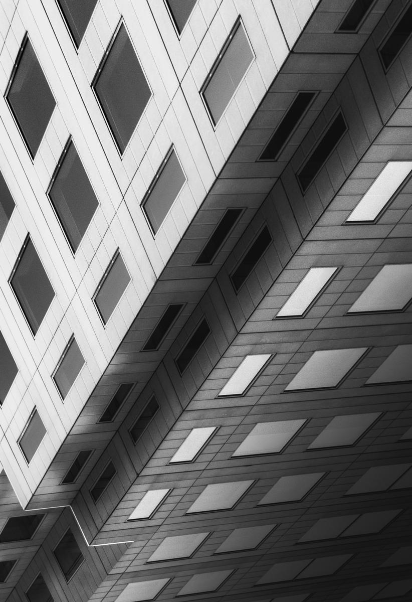 Yechang chen;Geometric Abstraction: Monochrome Facade;A striking black and white photograph capturing the angular elegance of a modern building, shot from a low perspective to emphasize its architectural symmetry and textured surface.